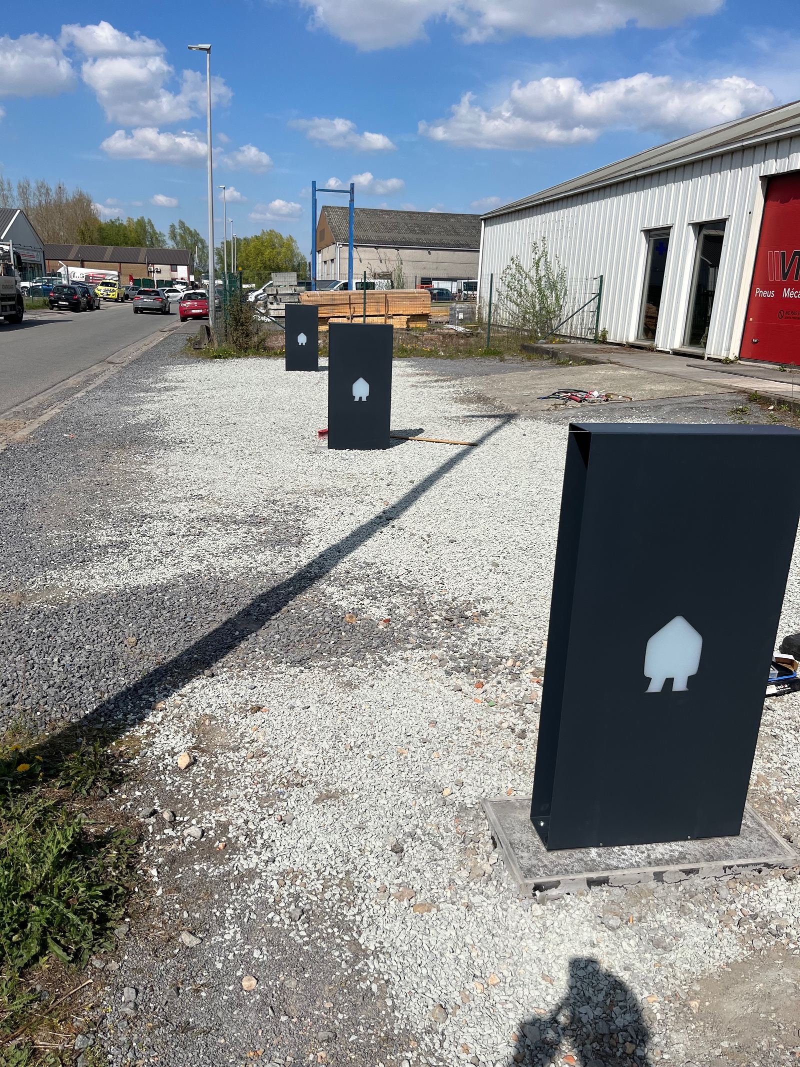 Trois bornes de rechargement alignées sur le parking d'une entreprise