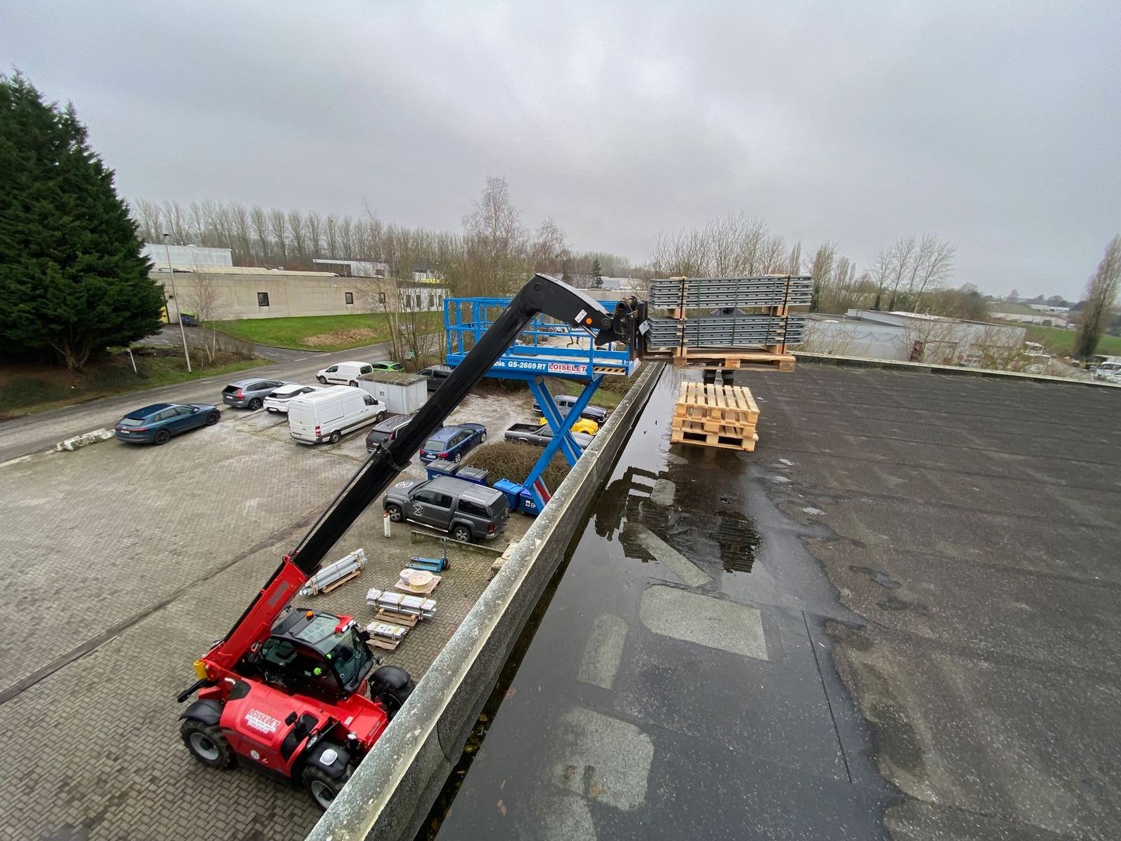 Chariot télescopique déposant des palettes de modules sur une toiture plate