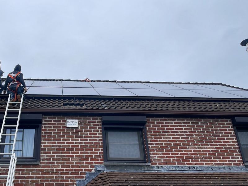 Pose de panneaux sur la toiture inclinée d'une maison en briques